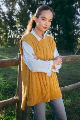 Chaleco mostaza de lana merino con tejido trenzado, corte oversized y largo asimétrico.