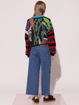 Pantalón de jean azul de corte ancho, tiro medio alto y largo a la altura del tobillo. Presenta apliques bordados con forma de labios.