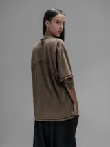 Remera de manga corta con diseño oversize, confeccionada en algodón con proceso batik artesanal en tono óxido. Presenta recortes superpuestos en el frente y costuras expuestas en mangas y cuerpo.