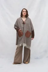 Chal de lana fina sin teñir con diseño de cuadros sutiles, cierre frontal con alamar y bolsillos de cuero metalizado. Presenta terminaciones con flecos en el ruedo y un calce estructurado en los hombros.