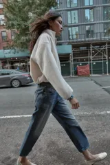 Chaqueta de textura bouclé en color crudo, con cuello subido, cierre frontal con cremallera, manga larga y puños elásticos.