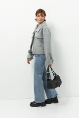 Tapado corto gris de paño, con cuello solapa grande, bolsillos de parche con solapa y mangas largas con puños anchos con presilla y aro metálico.