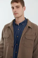 Sobrecamisa de tejido grueso sin forro, con diseño de corte holgado y silueta cuadrada. Presenta cuello clásico, cierre frontal con botones mate y dos bolsillos en el pecho con solapa.