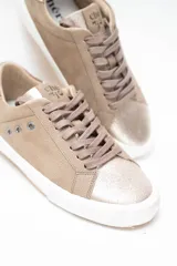 Championes de cuero legítimo color dorado con acabado metalizado, pasamontañas con cordones al tono y suela blanca con detalles de perforaciones laterales y talón contrastante.