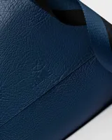 Bandolera color beige con correa ancha de tela negra con el nombre de la marca en blanco.