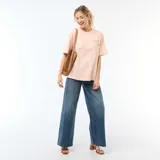 Camiseta oversize de color rosado con cuello redondo y mangas cortas. En la espalda presenta un estampado gráfico que incluye la leyenda "DELIZIOSO SICILIA", rayas verticales y frutas cítricas con hojas.