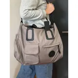 Bolso deportivo multifunción color negro, con diseño liso, compartimento principal con cierre, bolsillo frontal con solapa y bolsillo frontal con cierre. Cuenta con doble asa de mano y correa de hombro ajustable y extraíble. Incluye detalle de logo circular en la parte inferior.
