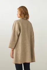 Tapado de largo medio abierto con cuello, confeccionado en lana fina sin teñir con detalles de terminación envivados en los bordes y mangas tres cuartos.