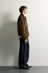 Cazadora de hombre regular fit confeccionada en tejido efecto ante, con acabado lavado, cuello solapa, manga larga, bolsillos de plastrón con solapa en la cadera, detalles elásticos en puños y cintura, y cierre frontal de cremallera.