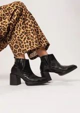 Botín negro de cuero con elástico lateral y cierre interno. Tiene plataforma delantera de 2 cm y taco de 8 cm.