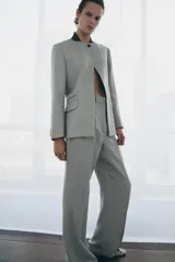 Pantalón de tiro medio con corte flare y pernera ancha. Presenta cintura con trabillas, bolsillos laterales, raya planchada frontal y cierre con cremallera, botón y ganchos metálicos.