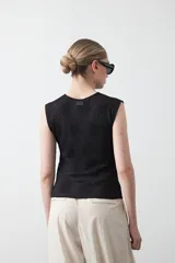 Top negro sin mangas con textura floral en relieve y diseño estructurado.