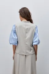 Chaleco de calce entallado color beige, de estilo cruzado con doble botonadura y escote redondo.