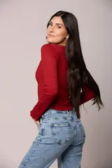 Jean de corte mom con tiro alto, confeccionado en denim de lavado claro con efecto desgastado. Presenta un diseño clásico de cinco bolsillos, cierre con cremallera y botón metálico.