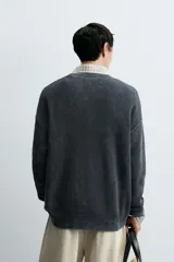 Jersey de punto con textura acanalada y efecto lavado, de corte relajado, cuello redondo y manga larga con puños y ruedo en rib.