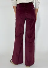 Pantalón de corte recto y tiro medio, confeccionado en pana color bordó. Presenta costuras verticales decorativas en el frente, cierre con botón y bolsillos laterales.