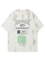 Remera de manga corta color nude con efecto tie-dye o goteo en tonos grises y blancos. Presenta un estampado gráfico frontal con tipografía estilo metal/rock, el texto "RETROGRADES", y el número "06" en verde menta.