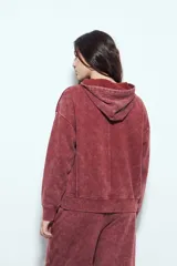 Buzo canguro color marrón oscuro con efecto lavado, calce relajado, capucha integrada, bolsillo frontal tipo canguro y terminaciones clásicas en puños y ruedo.