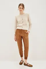 Pantalón tipo babucha de gabardina elastizada, color negro, con cintura elástica ajustable mediante cordón, puños en los tobillos, bolsillos diagonales frontales y bolsillos traseros con solapa y botón.