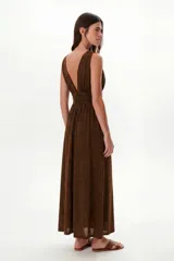 Vestido largo negro con brillo sutil, escote profundo en V y cintura marcada con frunces. Diseño sin mangas y falda amplia.