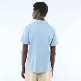 Remera de piqué de algodón color azul claro, con cuello polo sin botones y detalles de líneas blancas en el borde del cuello y las mangas.