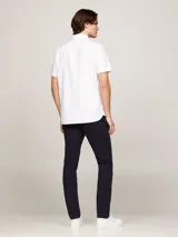 Camisa blanca de algodón Oxford, de corte regular, con cuello abotonado, manga corta y logo de Tommy Hilfiger bordado en el pecho.