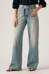 Jeans de corte recto y tiro alto, con diseño de pierna ancha y acabado lavado en tono celeste claro. Presentan cierre frontal con botón y cremallera, además de bolsillos laterales y traseros.