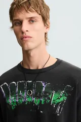 Camiseta boxy fit de punto tejido en hilatura de algodón, color negro con efecto lavado. Cuello redondo y manga corta. Estampado frontal con letras en blanco y verde.