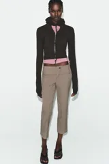 Sudadera cropped de punto con cierre frontal de cremallera metálica, capucha ajustable con cordones y mangas largas con puños en rib.