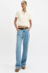 Top de punto color blanco marfil con cuello polo y manga corta. Presenta detalle de puntilla con forma de onda en el cuello y los puños.