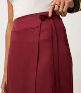 Pollera midi color bordó, estilo sobre, con traspase delantero alargado y lazo lateral con tiras finas. Posee cintura estructurada, caída recta y encaje discreto formado por la superposición de las capas. Confeccionada en viscolino (viscosa y lino).