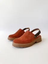 Zueco de cuero color ladrillo con correa trasera ajustable color marrón oscuro y suela track color marrón claro.