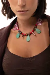 Collar corto de diseño artesanal compuesto por una combinación de cuentas de cristal checo, piedras facetadas, gotas de piedra turquesa y piezas alargadas de nácar teñido en tonos rojizos. Incluye cierre con ganchito y cadena de acero quirúrgico para ajuste de largo.