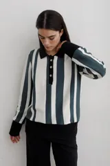 Buzo tipo polo de punto de algodón con diseño de rayas verticales en color blanco y verde oscuro. Presenta cuello y puños en color negro, cierre frontal con botones y corte recto.