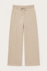 Pantalón de punto color beige, de corte recto y holgado. Presenta cintura elástica con cordón de ajuste y costuras verticales decorativas en el frente.
