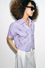 Camisa de cuello solapa y mangas cortas abullonadas, con diseño de rayas verticales en tonos rosados y celestes, decorada con lentejuelas bordadas.