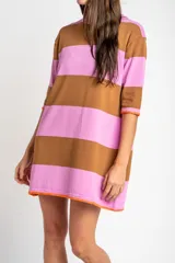 Vestido corto de tejido de punto con diseño de rayas horizontales anchas en color rosa y marrón. Presenta cuello redondo, mangas cortas y un detalle de borde en color naranja vibrante en las terminaciones de las mangas y el ruedo.