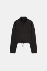 Sudadera de algodón con cuello subido y cierre frontal con cremallera. Presenta mangas largas, bolsillo tipo canguro frontal y bajo ajustable con cordones.