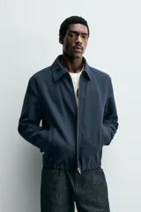 Cazadora boxy fit color azul marino, confeccionada en tejido de algodón. Presenta cuello solapa, manga larga con puño abotonado, bolsillos de vivo en la cadera y bajo elástico. Cierre frontal con cremallera.