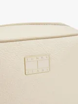 Bandolera Tommy Jeans color crema con logo tonal en el frente, correa ajustable y cierre de cremallera.