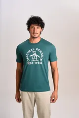 Remera de manga corta con cuello redondo, color verde oscuro, con estampa frontal del logo de la marca Original Penguin y la inscripción EST 1955 en color blanco.
