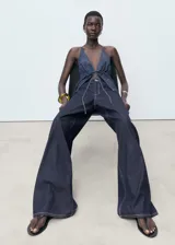 Pantalón de jean estilo wide leg, de tiro bajo y corte largo, con diseño de cinco bolsillos, trabillas para cinturón y cierre frontal con botón y cremallera.