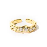 Anillo dorado ajustable con cinco zirconias engarzadas.