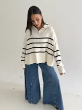 Sweater estilo chomba con cierre frontal, confeccionado en tejido bremer rayado de manga larga. Presenta un diseño amplio y moderno con cuello polo.