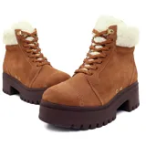 Botín acordonado de gamuza color marrón con cuello de piel sintética color crema. Tiene suela de goma color marrón oscuro con plataforma y taco cuadrado.