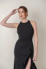 Vestido largo negro de crepe con spandex, corte recto con tajo alto y volados en el ruedo.