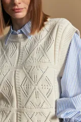 Chaleco tejido color crema con diseño de rombos calados, cuello redondo y sisas.