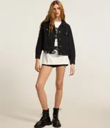 Campera de jeans de corte boxy, color azul medio lavado, con cuello, cierre frontal de botones, bolsillos con solapa y botones en el pecho, y recortes visibles.