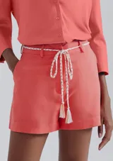 Short de lino en color crudo, de corte recto y tiro medio. Presenta una cintura con pasacintos y un cordón trenzado decorativo con borlas en el frente.