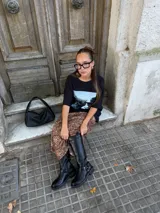 Conjunto compuesto por un remerón negro de algodón con estampa fotográfica frontal y una pollera midi de satén con estampado animal print de leopardo.